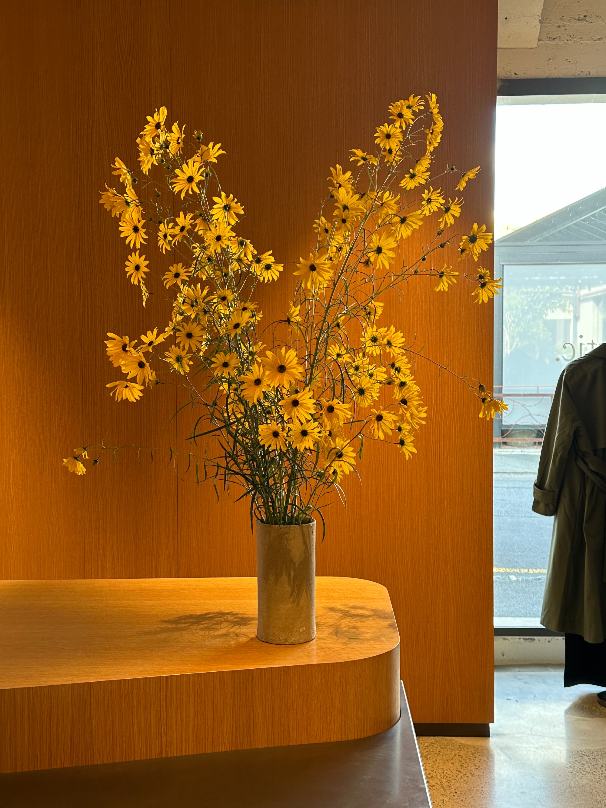 Yellow flowers in a vase on a wooden surface with a blurred background