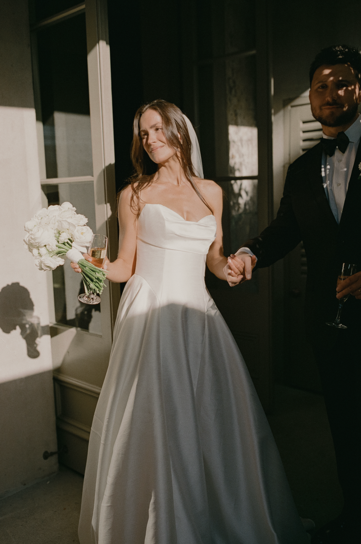 Woman in a white wedding dress holding hands with a man in a suit, holding bridal bouquet